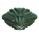 An otherworldly forest-green mask, with mouth agape like some kind of surreal forest-dwelling fish, faces forward but is viewed from above.